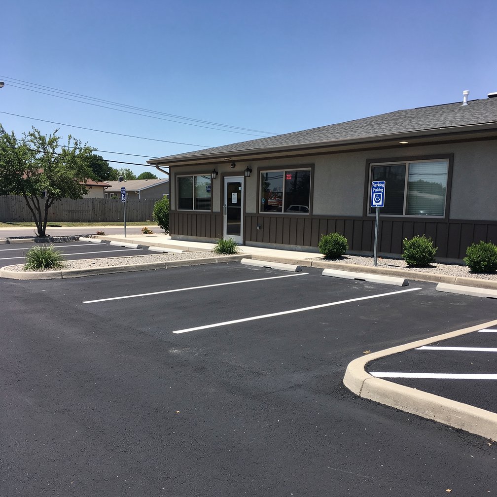 Small asphalt parking lot for a local business, neat line markings, sunny day, professional architectural photography